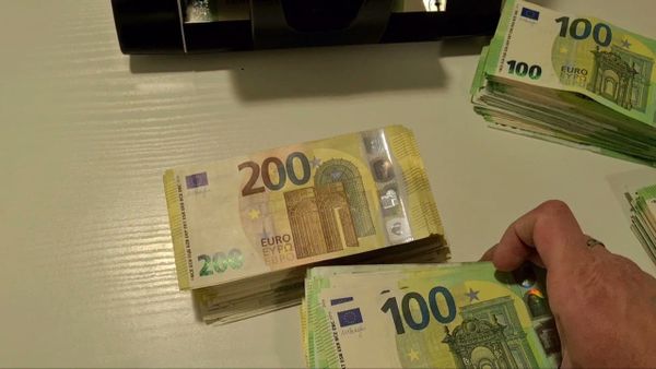 O persoană numără euro, multe bancnote de 100 și 200 euro