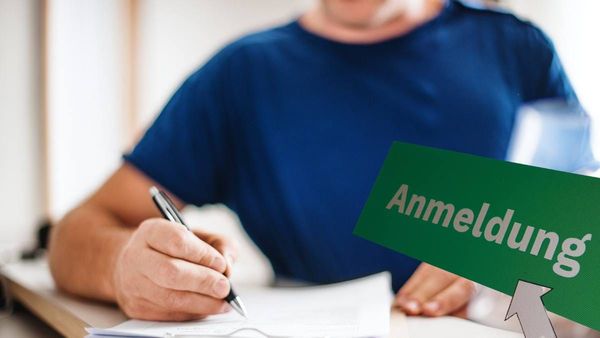 bărbat cu inscripția Anmeldung, înregistrarea oficială a adresei de domiciliu în Germania