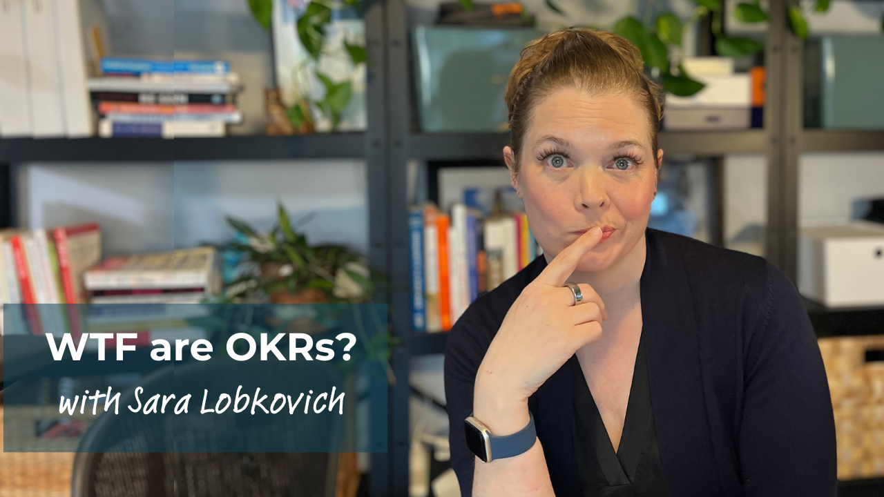 Sara is a dark blonde haired white woman, making a funny face at the camera with her finger over her mouth. The caption on th