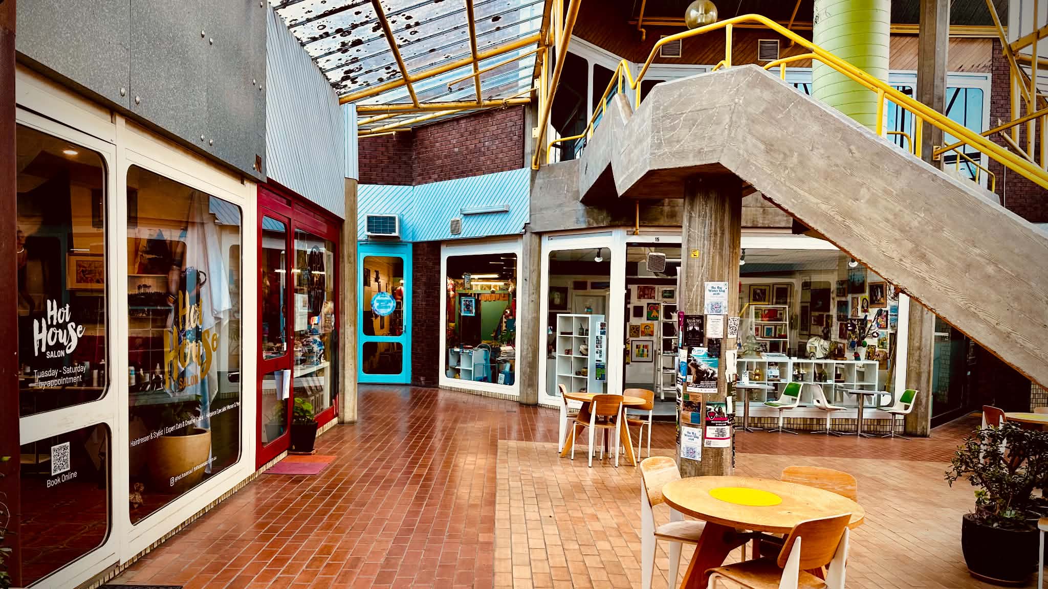 The covered central space of Centrepoint Arcade, with tables, shopfronts and a concrete staircase surrounded by Creative Geelong studios.