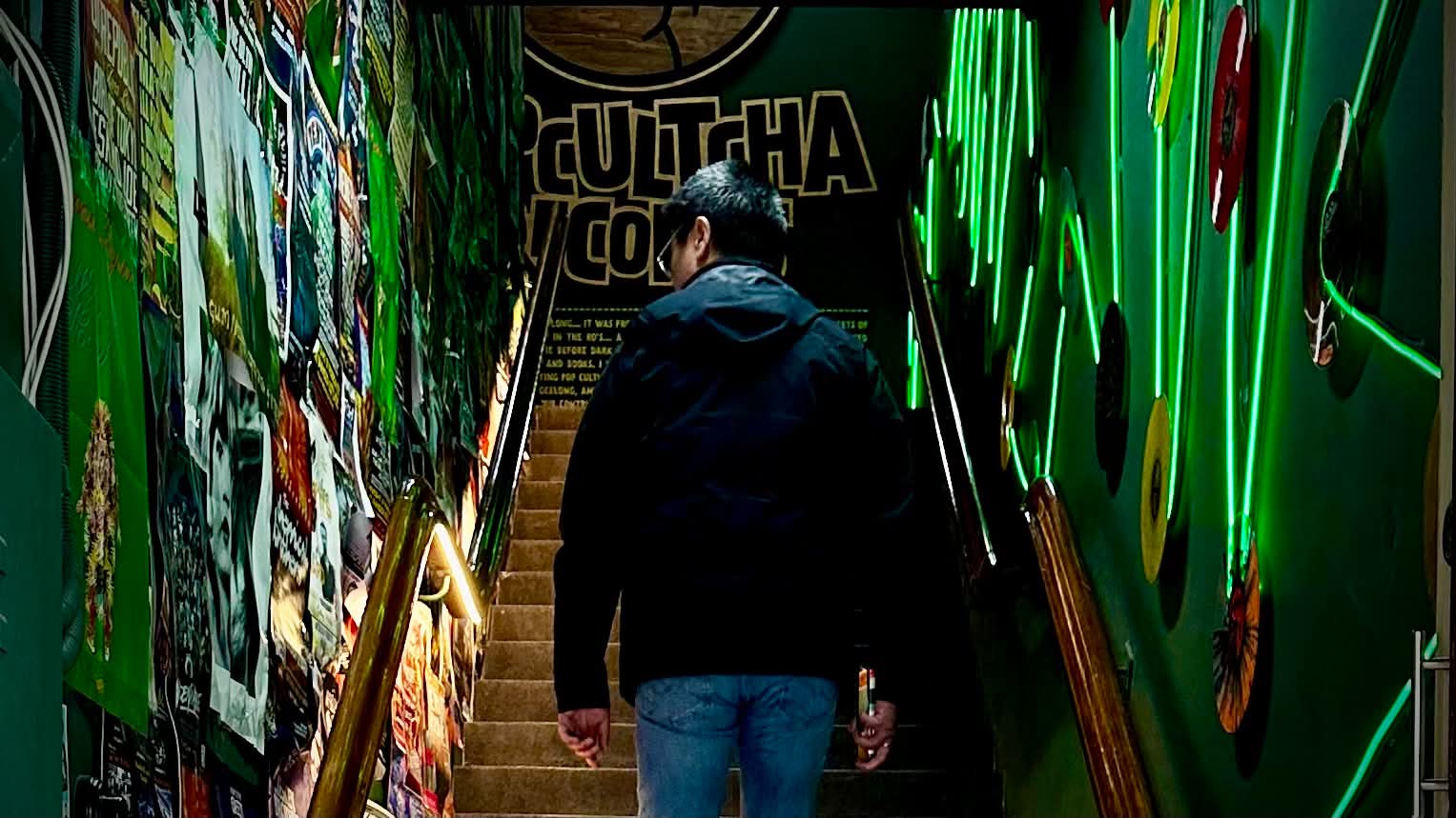 Jason climbs a narrow, green-lit staircase lined with records and posters at Popcultcha Records in central Geelong.