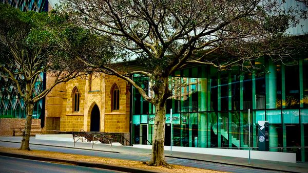 The stone façade of Church beside the glass-fronted Geelong Arts Centre, framed by winter trees on Ryrie Street.