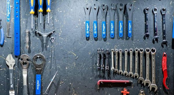View of a dark grey wall with various tools hanging in neatly organized rows