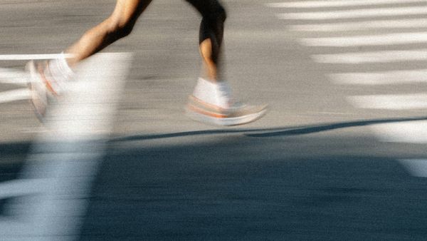 A runner's legs are shown against the backdrop of asphalt. The image is blurred, giving it a sense of movement.