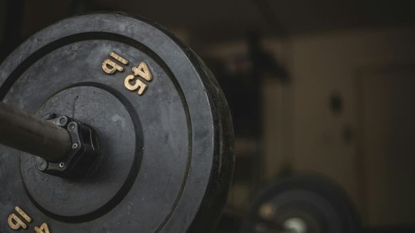 A barbell rests on the floor of a weight room