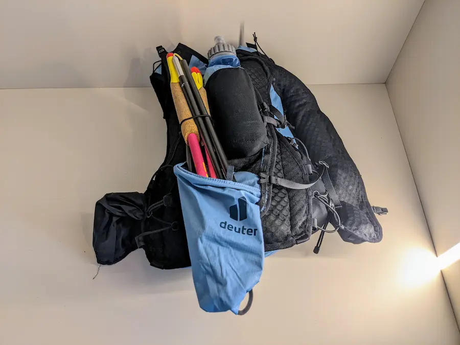 Système de fixation pour les bâtons de trail - sur les bretelles d'un sac noir et bleu