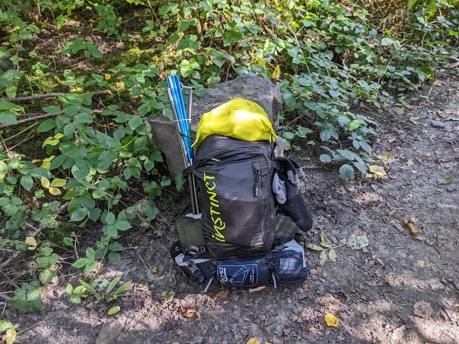 Sac de trail X8 18L d'Instinct posé sur une roche au milieu d'un sentier de terre