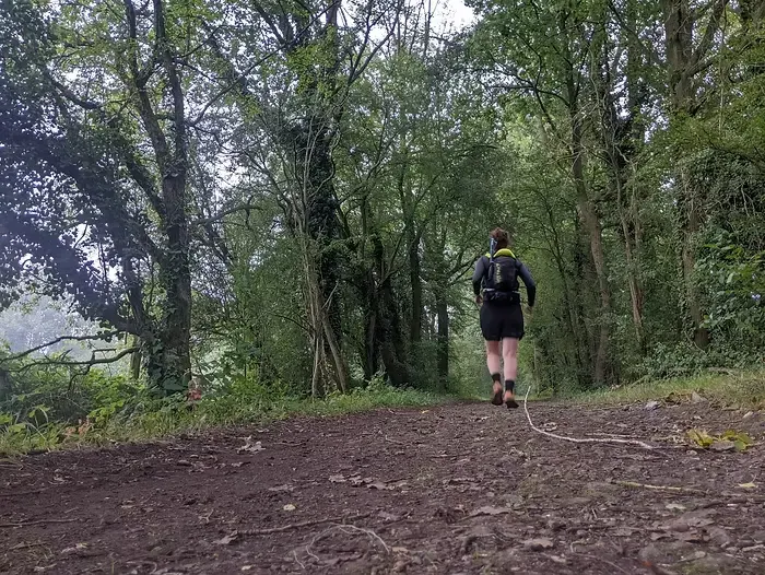 Femme courant avec un sac sur le dos sur un sentier de terre