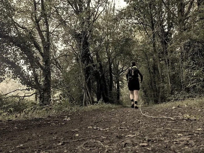 Femme courant avec un sac sur le dos sur un sentier de terre