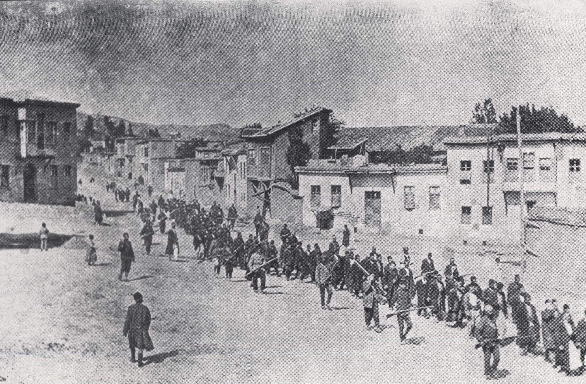 Fotografia del 1915: una columna d'homes armenis conduida per soldats otomans armats pels carrers de Kharput