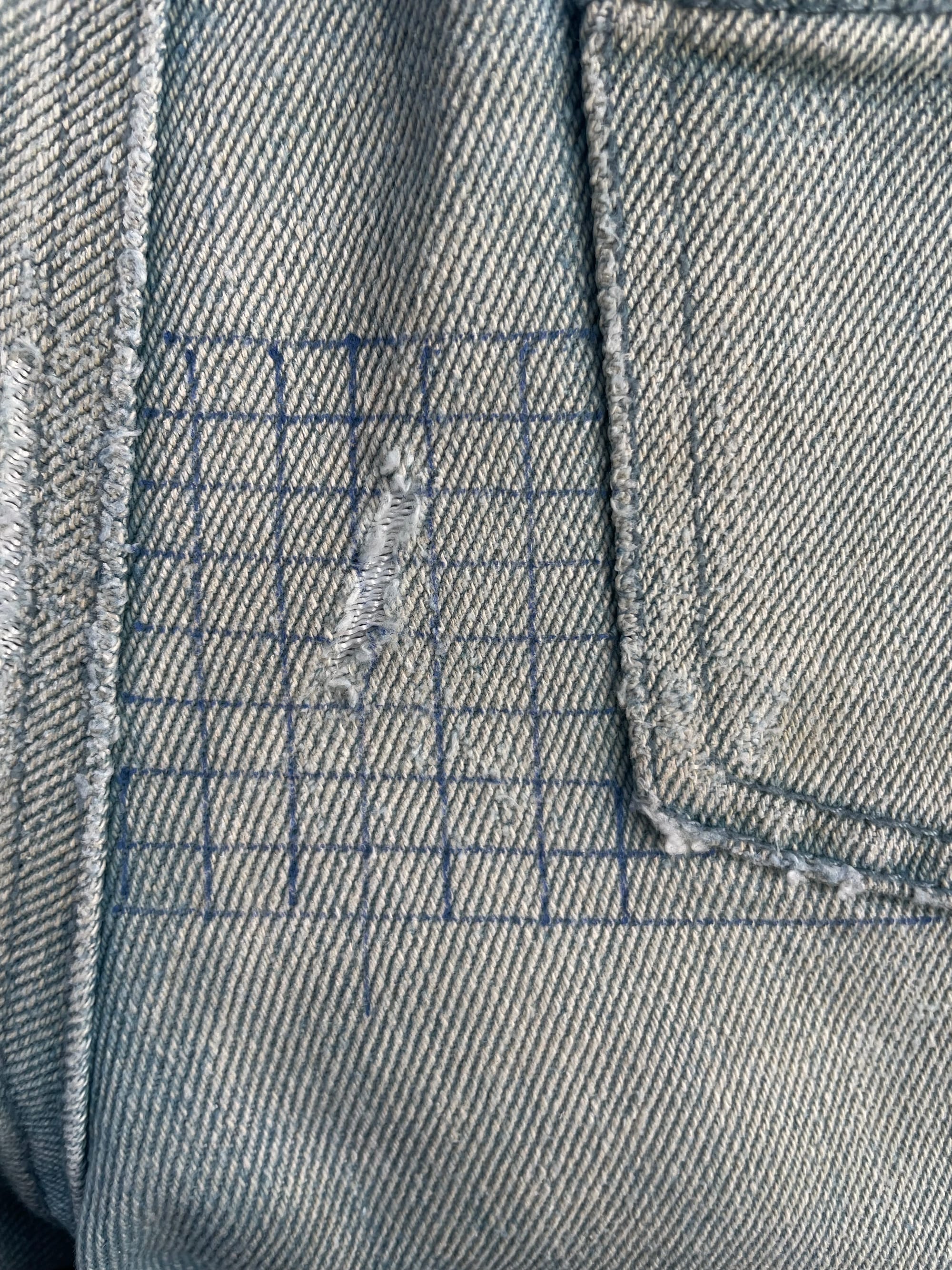 Denims about to develop a hole prepared to be patched by drawing a sewing guide grid.