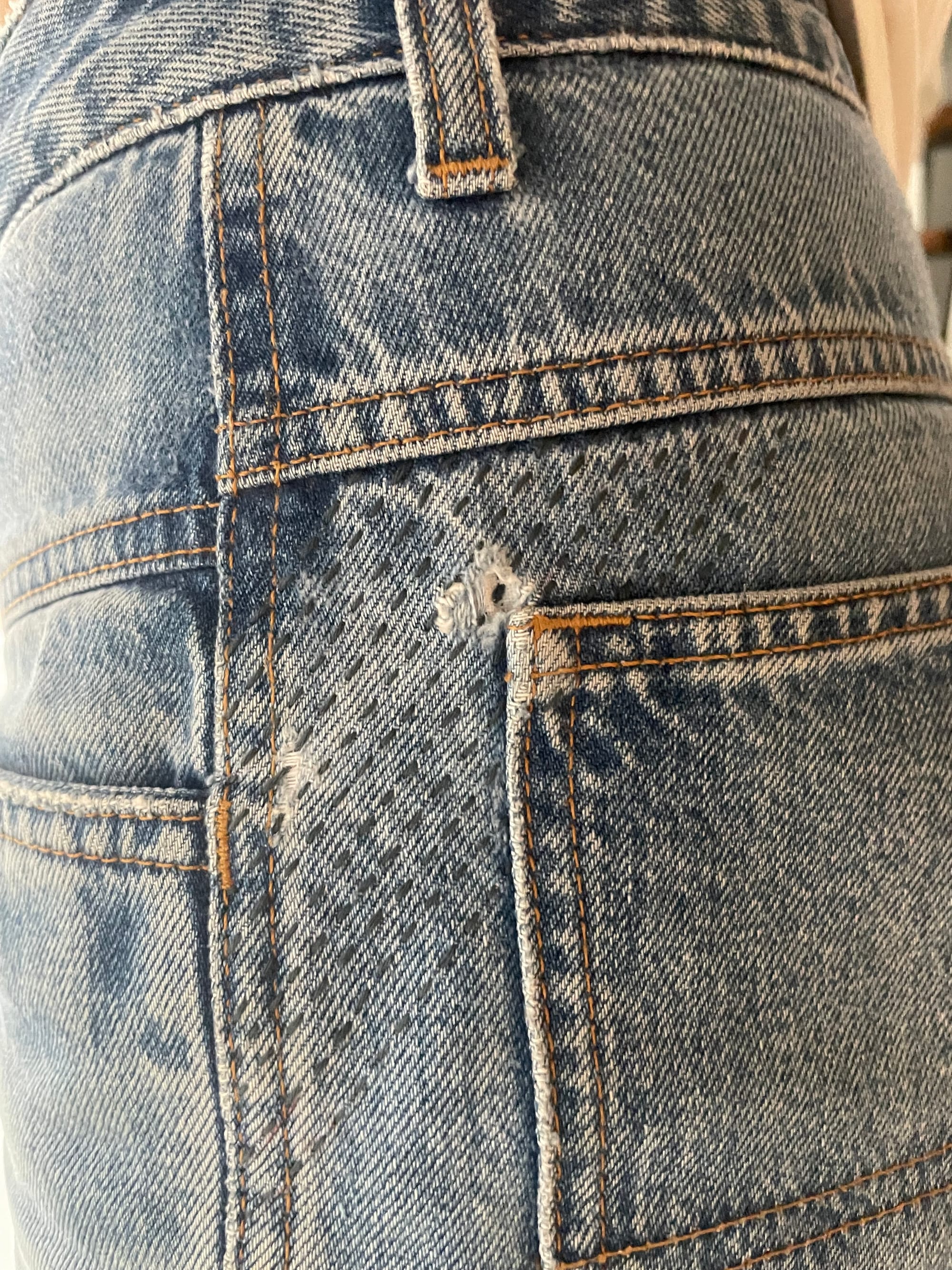 Denims mended with dark blue sashiko lines at the back pocket