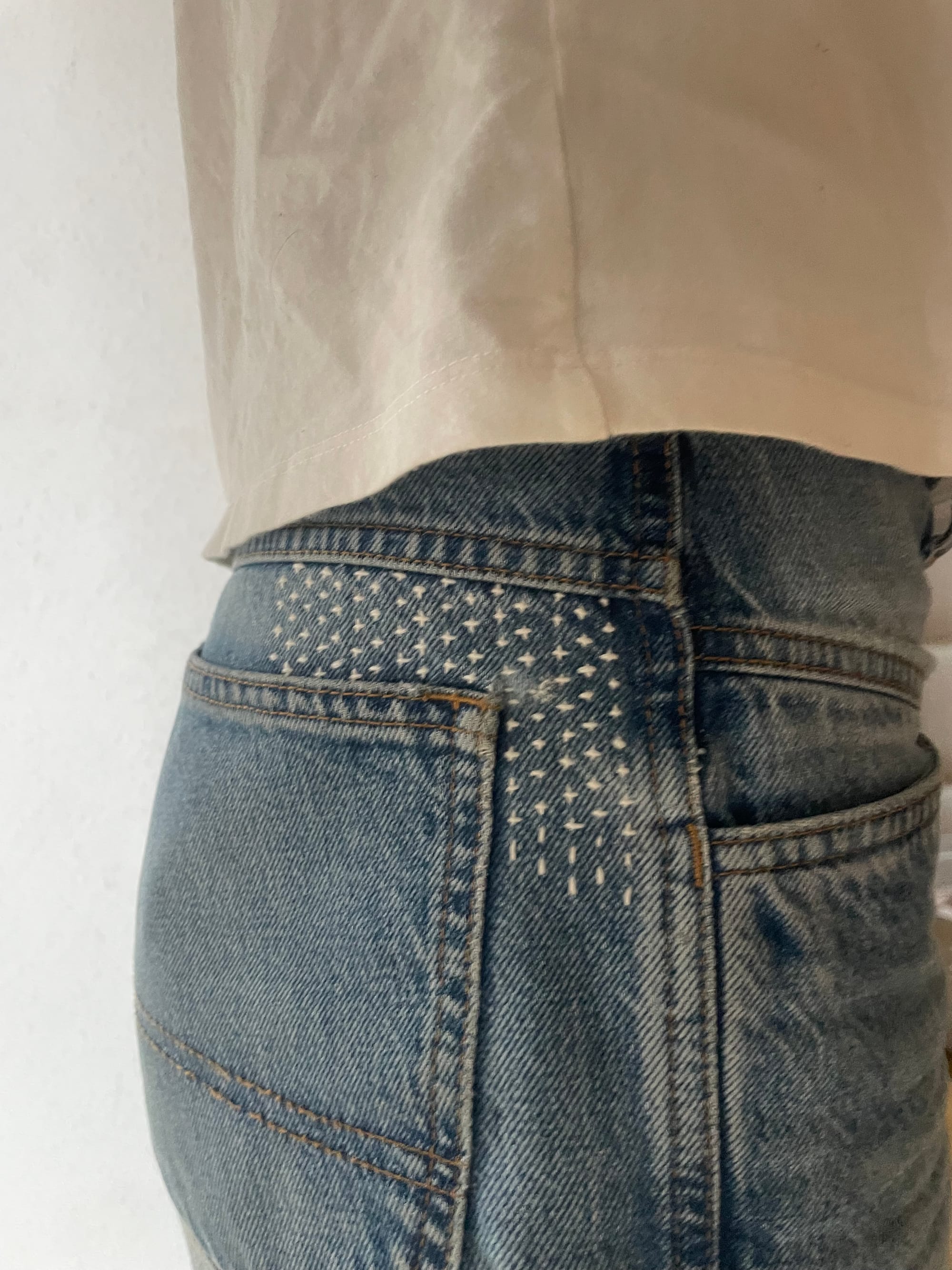 Blue denims mended with sashiko pattern jujizashi in white at the back pocket