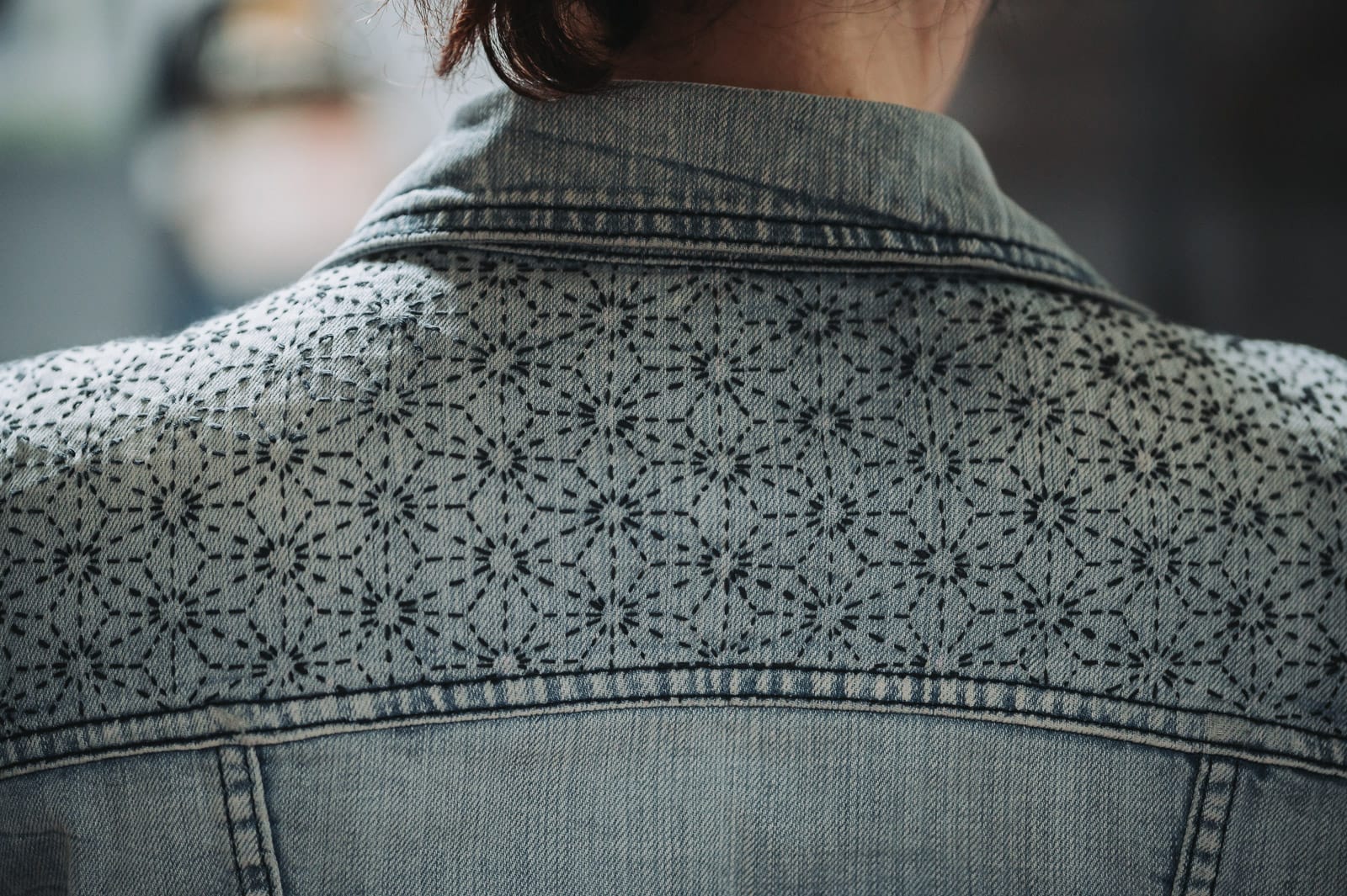 The back of a denim jacket partly embellished with the asanoha sashiko pattern in indigo.