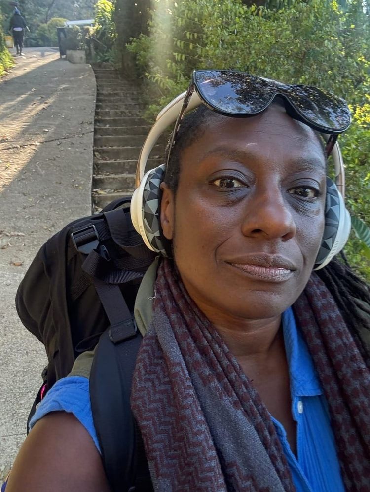 Atena walking down the mountain, above Antigua, Guatemala,wearing a blue dress and her Black-on-Black kuffiyah.