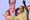Maharashtra politician Uddhav Thackeray, wearing a beige kurta, stands in front of a mike with his arms spread out. In the ba