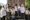 A group of eight Kashmiri boys and girls, dressed in school uniforms and carrying schoolbags and water bottle, pose for a pho