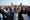 A large crowd of Pashtun men dressed in their traditional attire of kurta and salwar raise their hands as they appear to chee