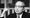 A black-and-white photograph of U Thant, the Burmese diplomat and former UN secretary-general, seated behind a microphone with his fist raised near his face