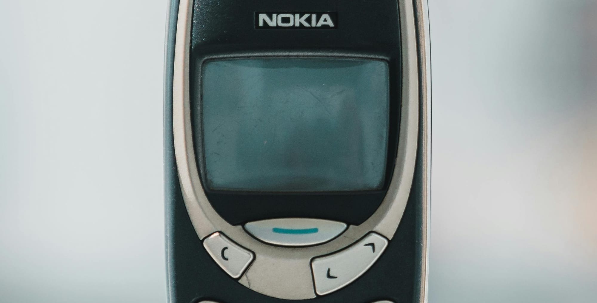A close-up of a classic Nokia 3210 mobile phone, with its iconic design and physical keypad, placed against a neutral background. The phone evokes nostalgia and simplicity, representing a step away from modern smartphone dependency.