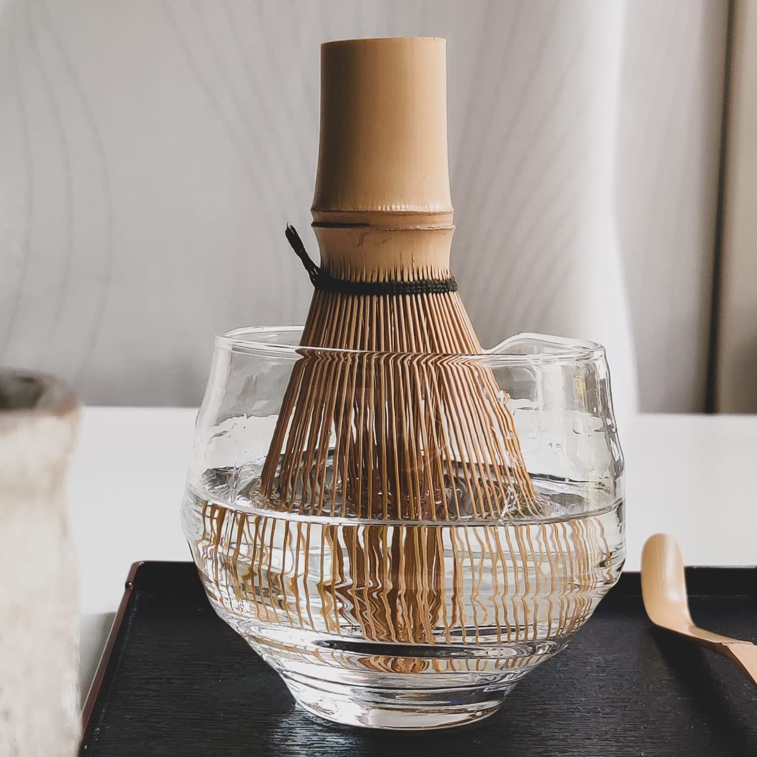 A chasen (bamboo whisk) sitting in a bowl of water. Photo credit @janschanoma