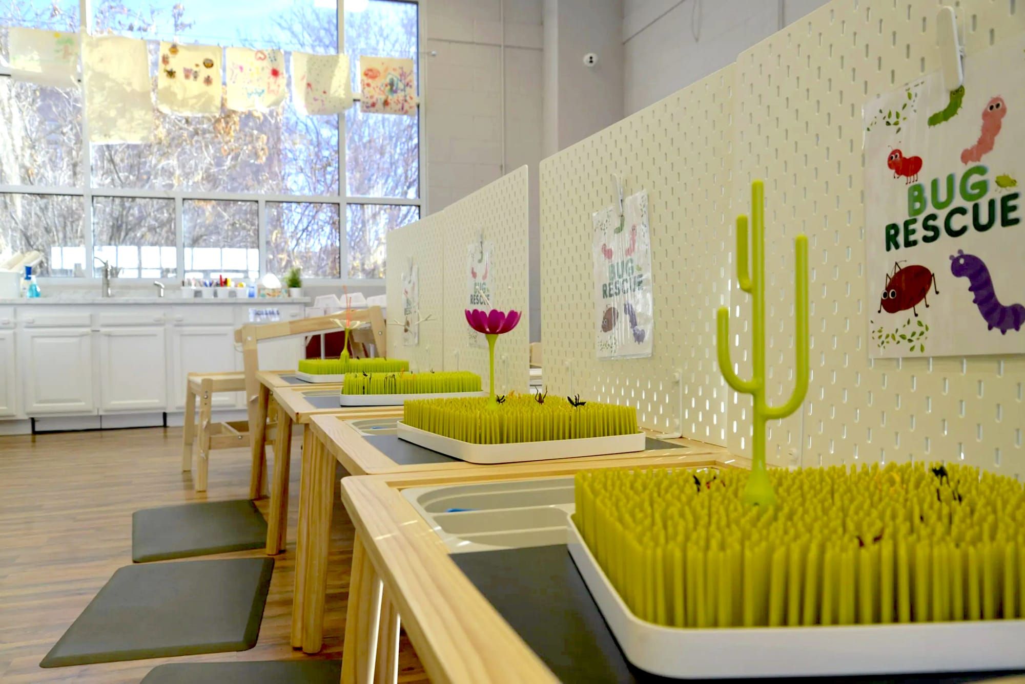 Photo of 3 tables with trays of rubber whiskers and bins of "insects" to place in the "grass."