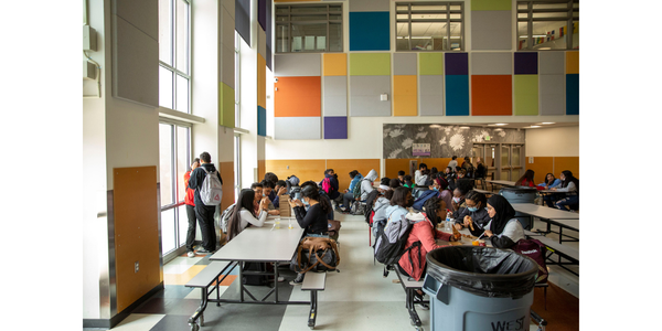 Photo of high school students eating lunch at foldable tables with benches.  