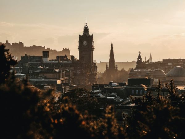 Klokketårnet på Balmoral Hotel og Scott Monument i Edinburgh sett fra Calton Hill i varmt kveldslys.