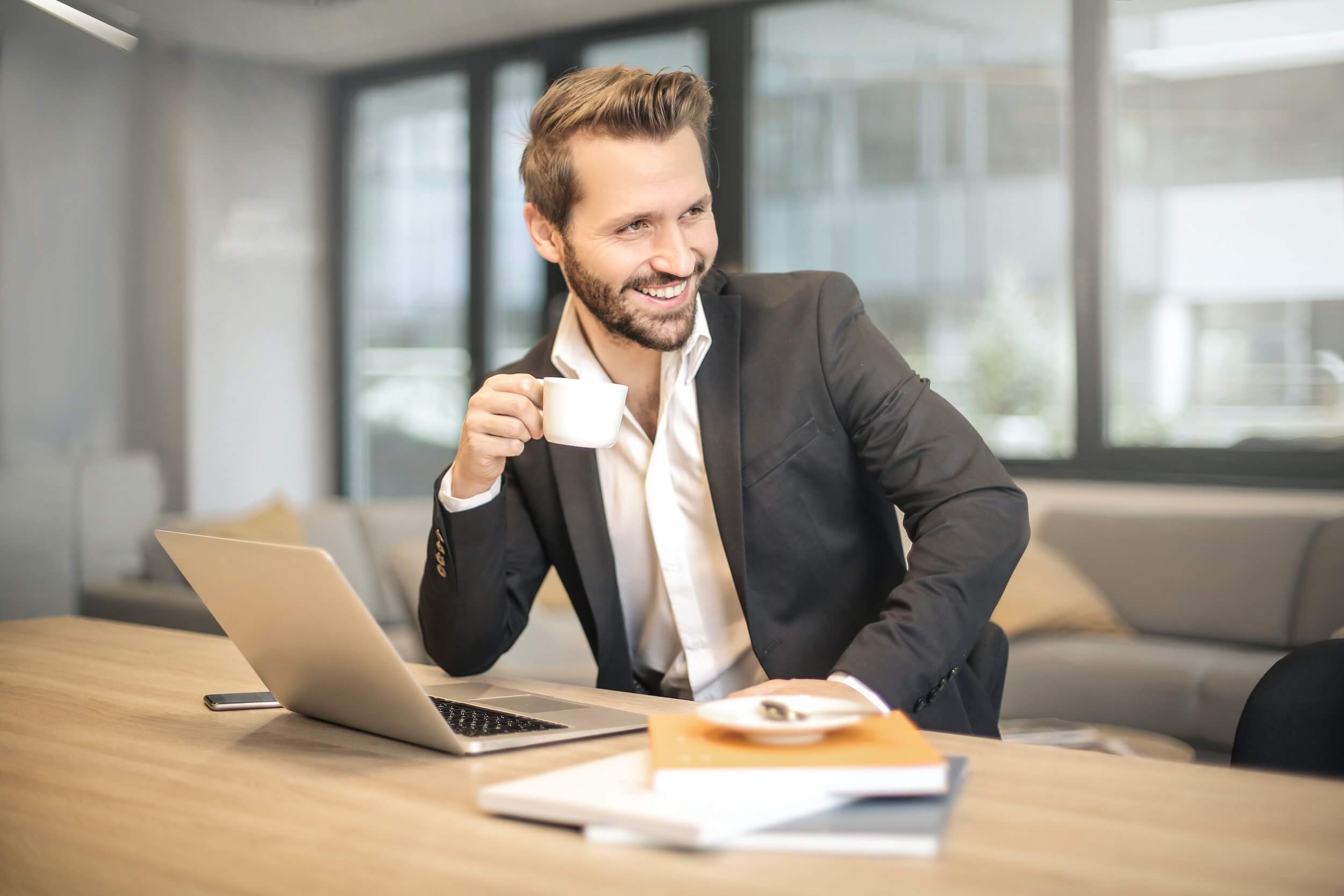 Business man with with open collar and white coffee cup his hand.