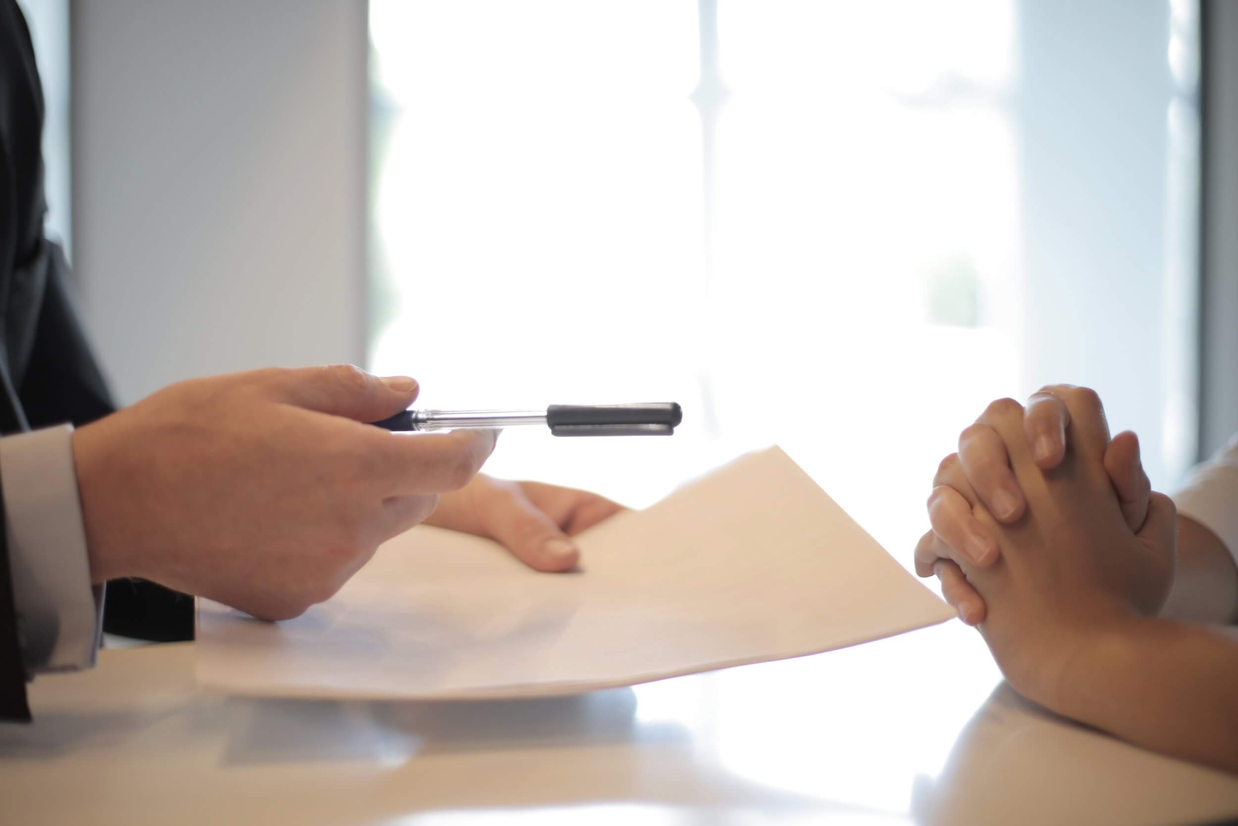 Close-up photo of two pairs of hands over an interview table.