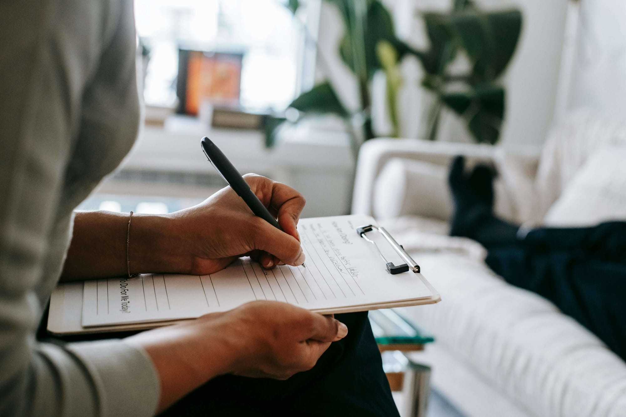 A healthcare professional taking notes at a patient's bedside