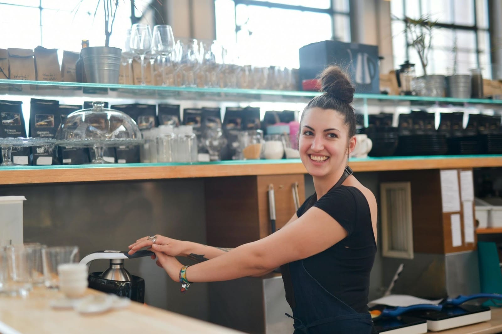 A young female barista smiling to someone off camera as she works.