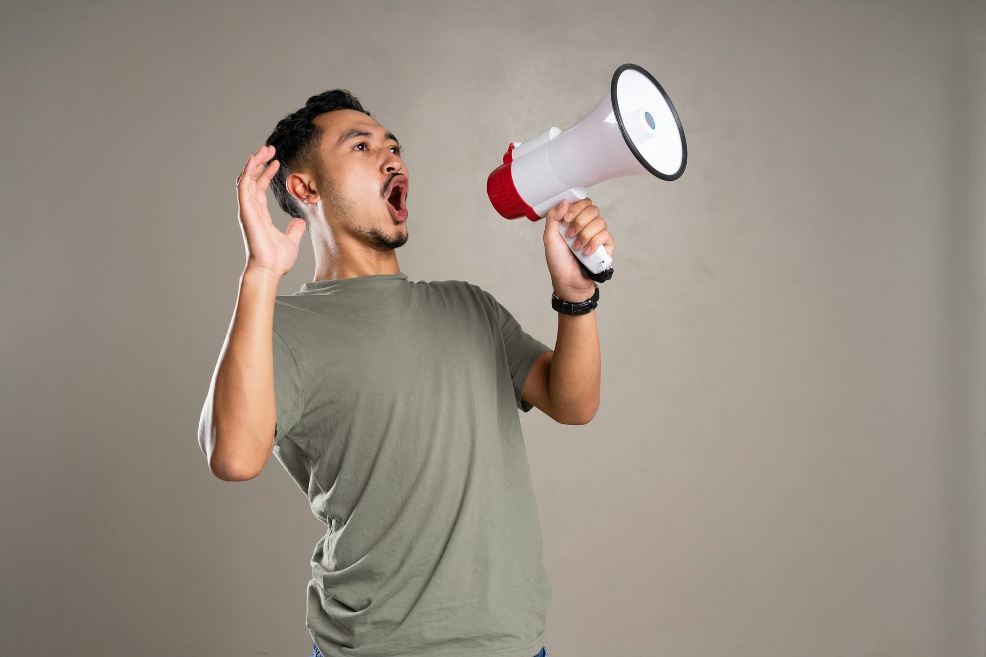 A man in a grey t-shirt leaning back and yelling into a megaphone.