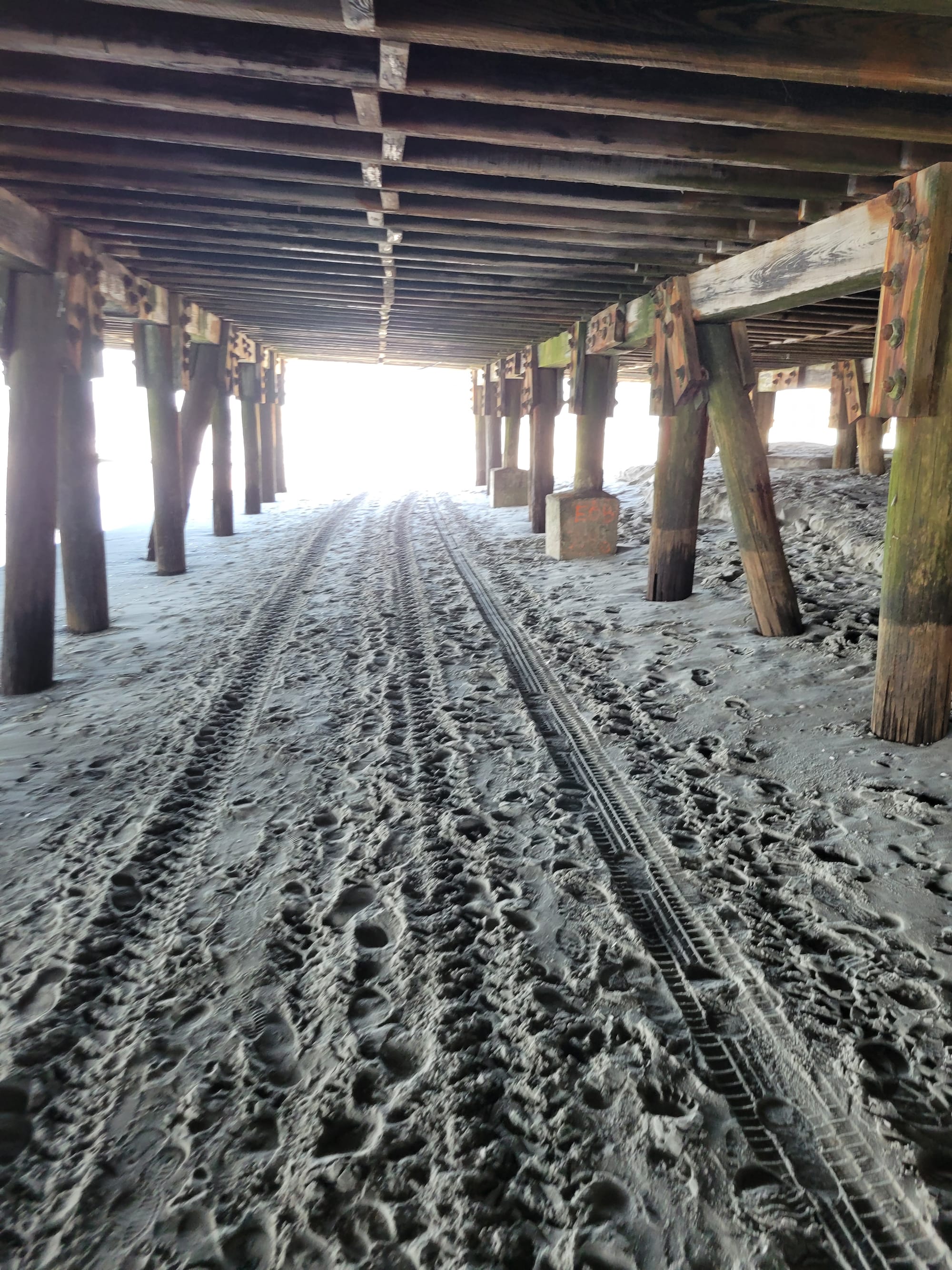 Photo of sand underneath the pilings of a boardwalk