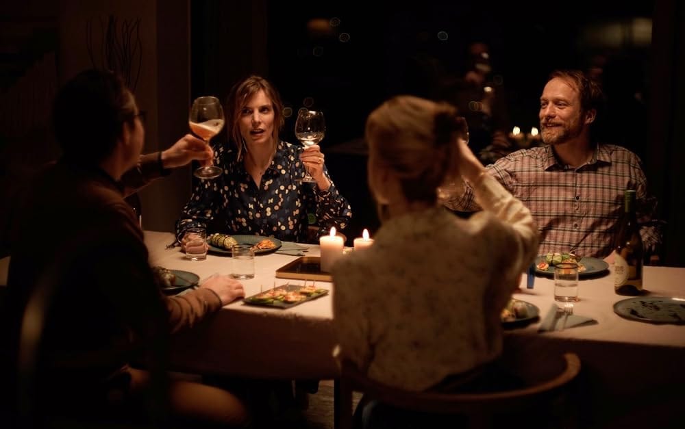 A couple raises their glasses with their hosts at dinner. Everyone is still alive and kind of happy.