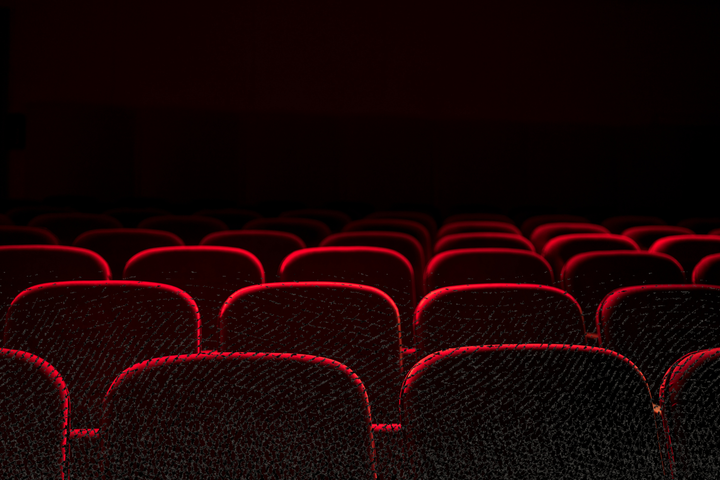 An image of movie theater seats in a dark room