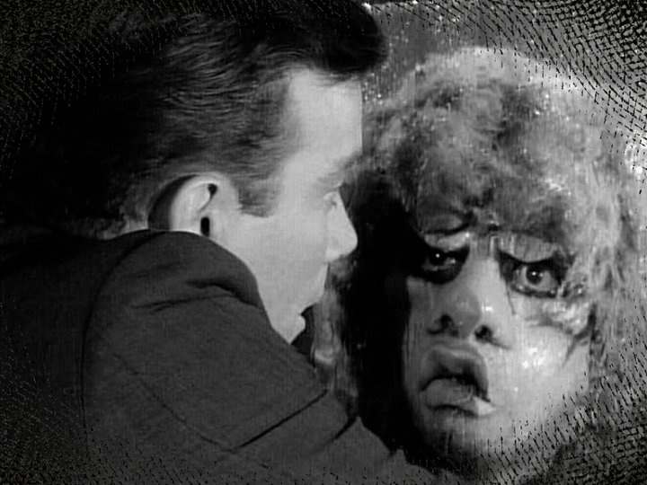william shatner looking out an airplane window in horror as a creature with a grotesque face looks back at him from the wing