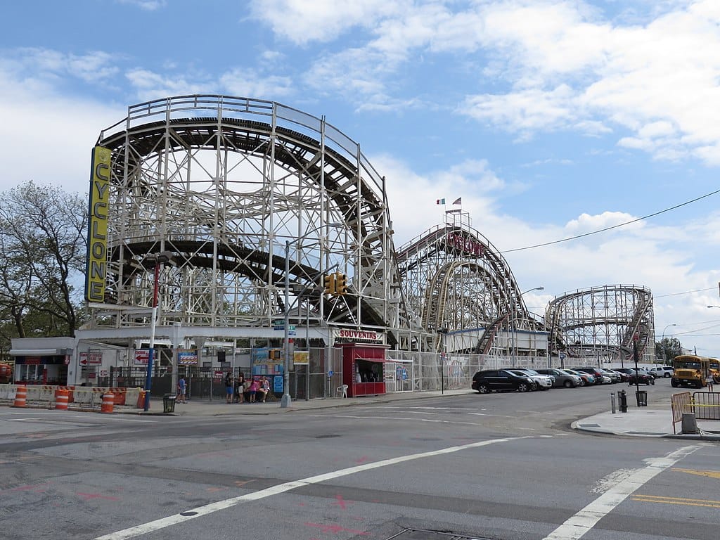 A roller coaster situated along a city street with a sign reading “Cyclone”