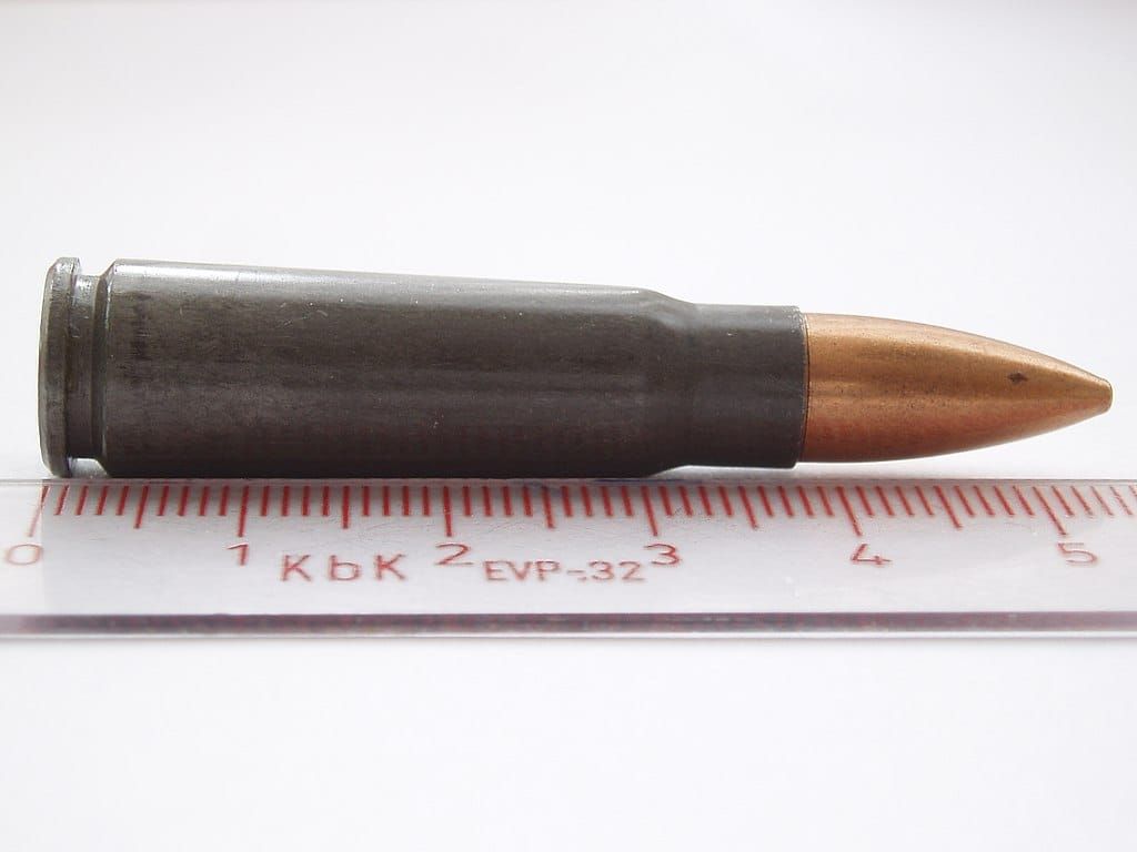 Photo of a rifle cartridge with the lead bullet encased in harder metal; a ruler shows the cartridge is about 5.5 cm long