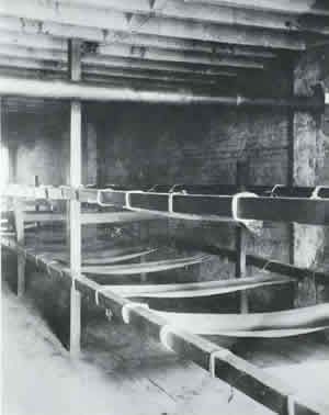A squalid room with two levels of hammock-style bunks lining the walls