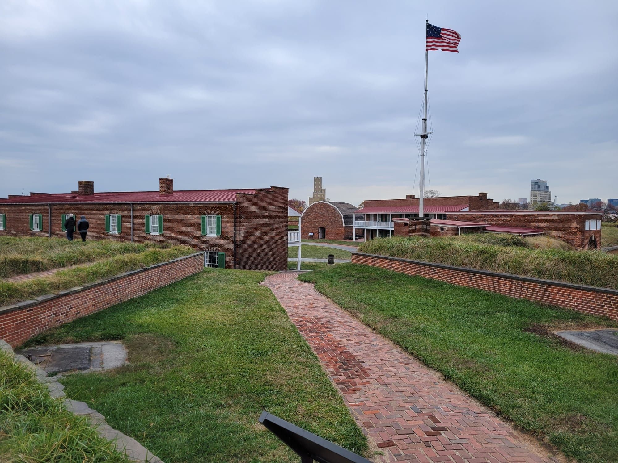 An early 19th-century fort, brick buildings surrounded by earthen battlements, with a 15-star American flag flying overhead