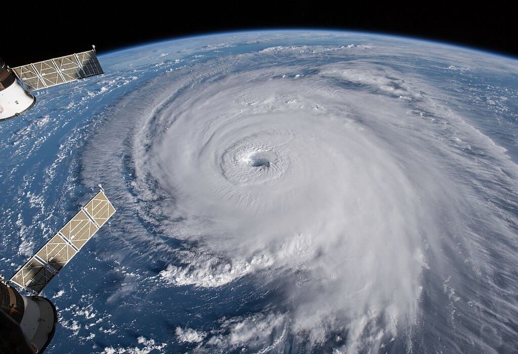 Photo from space of a large hurricane, solar panels of the International Space Station are in the foreground