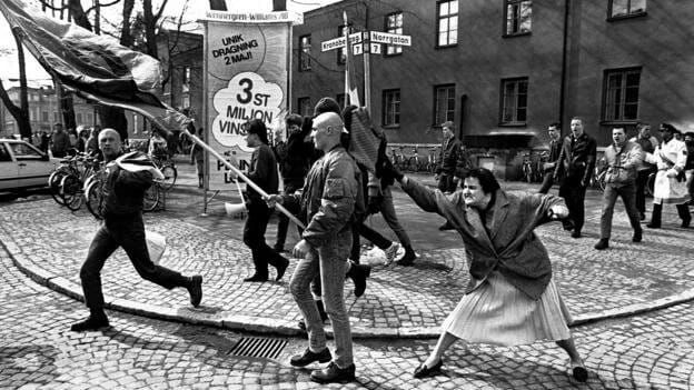 B&W photo of woman hitting a neo-Nazi from behind with her handbag