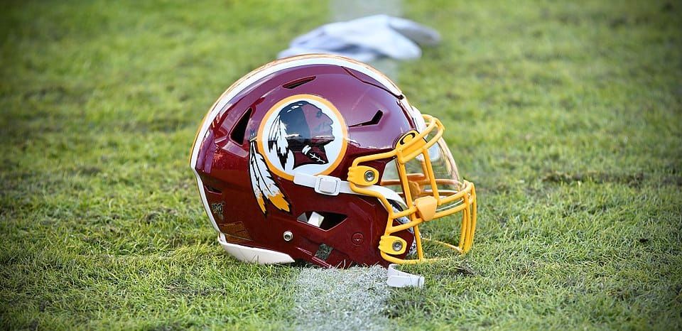 Photo of a maroon football helmet sitting on a football field that bears a profile image of a Native American man