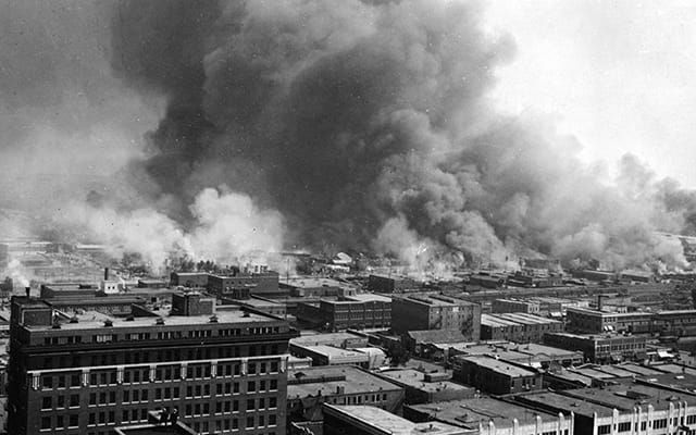 B&W photo of smoke billowing from a city on fire