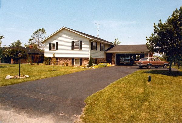 A house and green lawn; a car is parked in the driveway and a van in the garage