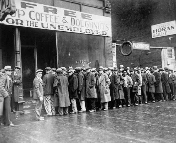 B&W photo of men queued before a storefront with a sign reading “Free Soup Coffee & Doughnuts for the Unemployed"