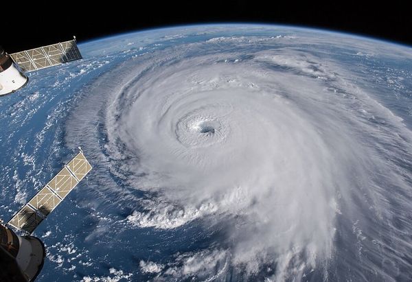 Photo from space of a large hurricane, solar panels of the International Space Station are in the foreground