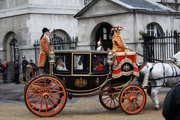Photo of an ornate horse-drawn carriage with driver and footmen in 18th-century dress