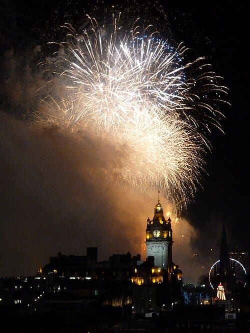 Fireworks exploding over a cityscape featuring a clock tower